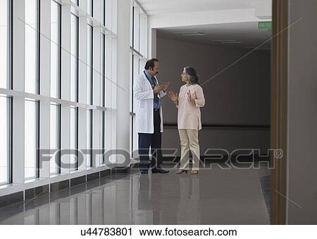Stock Image - Doctor discussing patient care in hospital corridor. Fotosearch