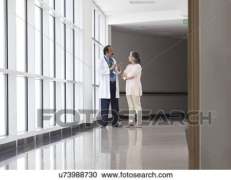 Doctor discussing patient care in hospital corridor View Large Photo Image Stock Image - Doctor discussing patient care in hospital corridor. Fotosearch