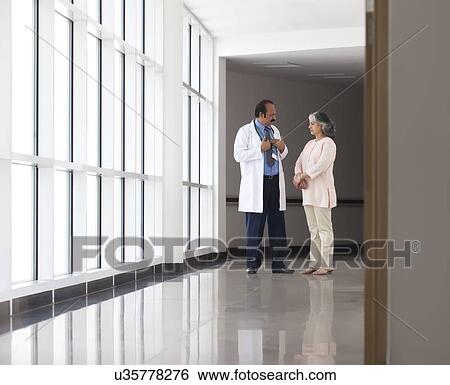 Stock Photograph - Doctor discussing patient care in hospital corridor. Fotosearch