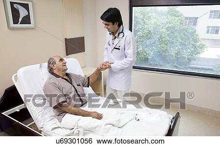 Stock Photograph - Doctor holding his patient's hand . Fotosearch