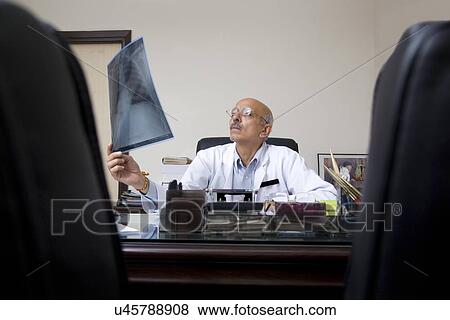 Doctor looking at an X-ray View Large Photo Image Stock Photo - Doctor looking at an X-ray . Fotosearch