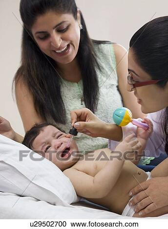 Doctor putting drops into a babies mouth View Large Photo Image Stock Image - Doctor putting drops into a babies mouth . Fotosearch