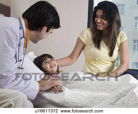 Stock Image - Doctor sitting with a little girl and her mother . Fotosearch