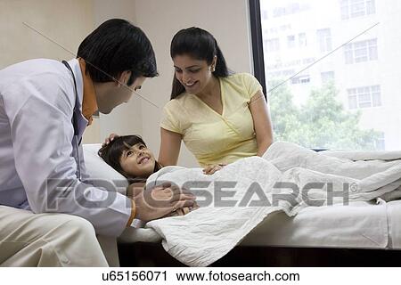 Stock Image - Doctor sitting with a little girl and her mother . Fotosearch