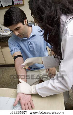 Stock Image - Doctor taking a blood sample from a man . Fotosearch