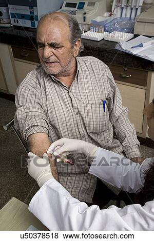 Stock Photo - Doctor taking a blood sample from a man . Fotosearch