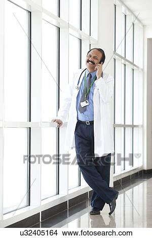 Doctor talking on a mobile phone View Large Photo Image Picture - Doctor talking on a mobile phone. Fotosearch
