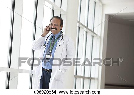 Doctor talking on a mobile phone View Large Photo Image Picture - Doctor talking on a mobile phone. Fotosearch