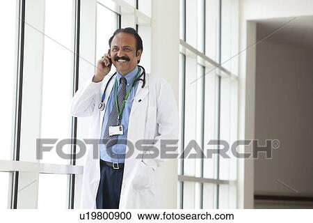 Stock Image - Doctor talking on a mobile phone. Fotosearch