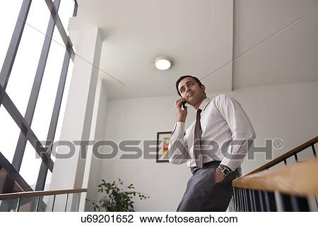 Stock Image - Executive on staircase talking on a mobile phone. Fotosearch
