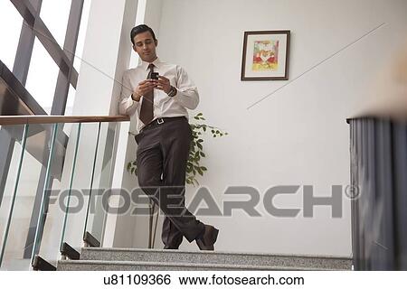 Stock Photograph - Executive reading an sms on a mobile phone. Fotosearch
