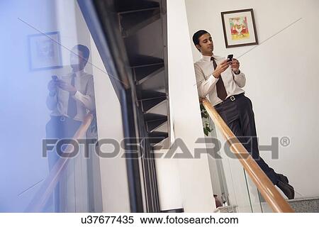 Executive reading an sms on a mobile phone View Large Photo Image Stock Photography - Executive reading an sms on a mobile phone. Fotosearch