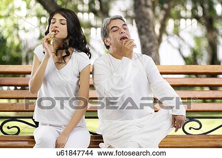 Father and daughter eating chocolate in a park View Large Photo Image Picture - Father and daughter eating chocolate in a park . Fotosearch