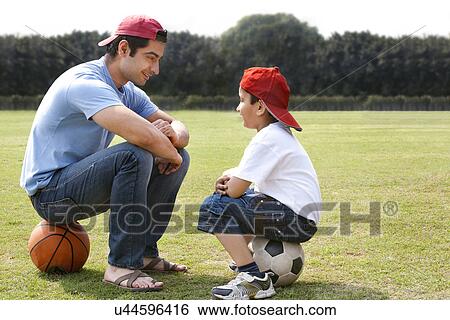 Father and son sitting face to face View Large Photo Image Stock Photograph - Father and son sitting face to face . Fotosearch