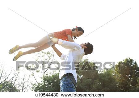 Stock Image - Father lifting his daughter in the air . Fotosearch
