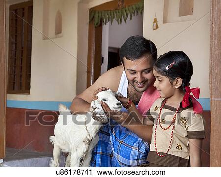 Stock Image - Father showing a goat to his daughter . Fotosearch