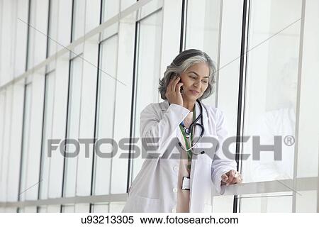 Female doctor talking on a mobile phone View Large Photo Image Stock Photography - Female doctor talking on a mobile phone. Fotosearch