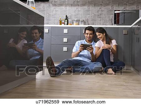Full length of relaxed couple using digital tablet in kitchen View Large Photo Image Stock Photo - Full length of relaxed couple using digital tablet in kitchen. Fotosearch