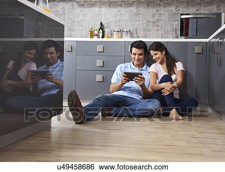 Full length of smiling couple using digital tablet together in kitchen View Large Photo Image Stock Photograph - Full length of smiling couple using digital tablet together in kitchen. Fotosearch
