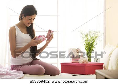Stock Image - Girl admiring gifts in her hand . Fotosearch
