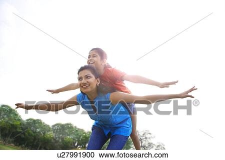 Girl balancing on her mothers back View Large Photo Image Stock Image - Girl balancing on her mothers back . Fotosearch