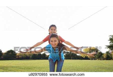 Girl balancing on her mothers back View Large Photo Image Stock Photography - Girl balancing on her mothers back . Fotosearch