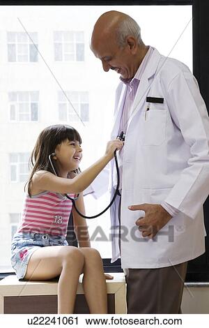 Stock Image - Girl checking a doctor's heartbeat . Fotosearch