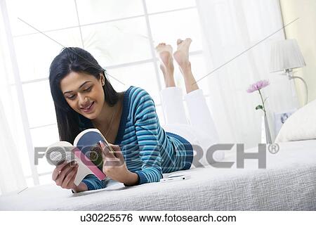 Stock Photograph - Girl enjoying reading a book in bed . Fotosearch