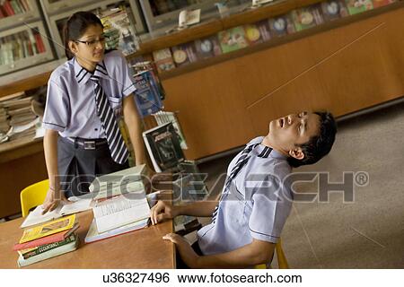 Stock Photograph - Girl looking at a boy sleeping on a chair . Fotosearch