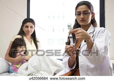 Girl looking at a doctor with a syringe View Large Photo Image Picture - Girl looking at a doctor with a syringe . Fotosearch