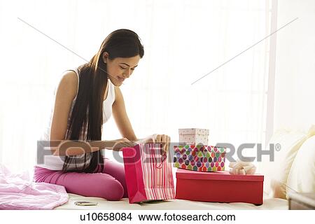 Picture - Girl looking for more gifts in a bag . Fotosearch