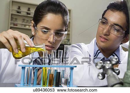 Stock Image - Girl pouring a liquid into a test tube . Fotosearch