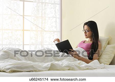 Picture - Girl reading a book in bed . Fotosearch