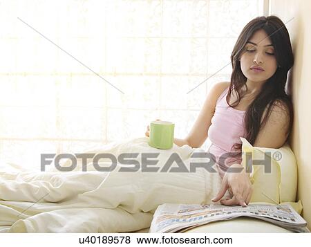 Stock Photo - Girl reading a newspaper in bed . Fotosearch