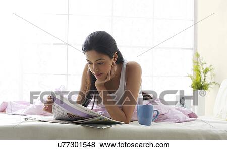 Girl reading a newspaper in bed View Large Photo Image Stock Photo - Girl reading a newspaper in bed . Fotosearch