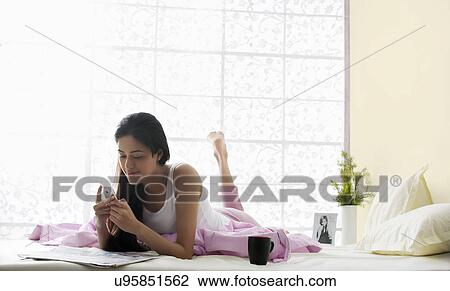 Stock Image - Girl reading an sms in bed . Fotosearch