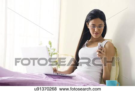 Girl reading an sms in bed View Large Photo Image Stock Photo - Girl reading an sms in bed . Fotosearch