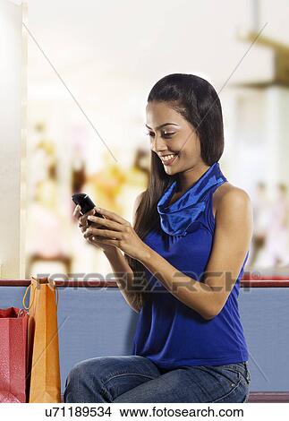 Girl reading an sms on her mobile phone View Large Photo Image Picture - Girl reading an sms on her mobile phone . Fotosearch
