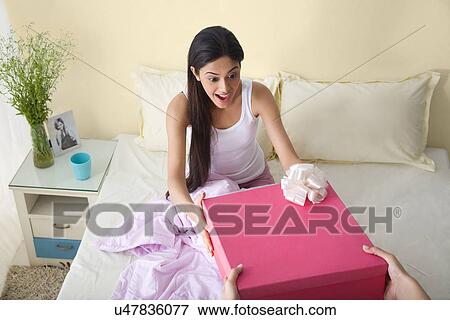Girl receiving a birthday gift in bed View Large Photo Image Stock Photo - Girl receiving a birthday gift in bed . Fotosearch
