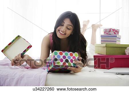 Girl smiling at the contents of a gift box View Large Photo Image Stock Image - Girl smiling at the contents of a gift box . Fotosearch