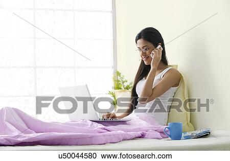 Stock Image - Girl talking on a mobile phone while working . Fotosearch
