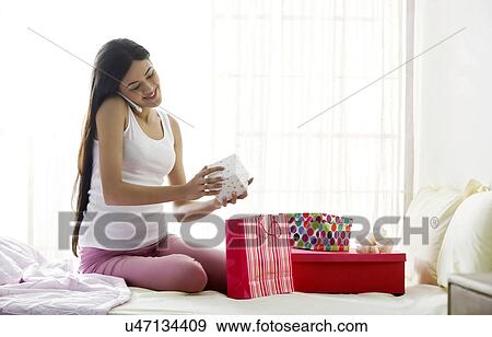 Girl talking on a mobile phone while holding a gift View Large Photo Image Stock Photo - Girl talking on a mobile phone while holding a gift . Fotosearch