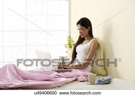 Girl working on a laptop in her bedroom View Large Photo Image Stock Image - Girl working on a laptop in her bedroom . Fotosearch