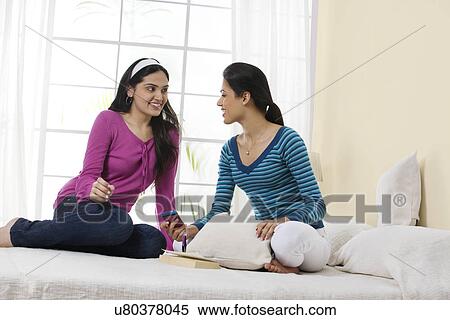 Stock Photography - Girls discussing a message on a mobile phone . Fotosearch