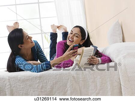 Picture - Girls laughing at a message on a mobile phone . Fotosearch