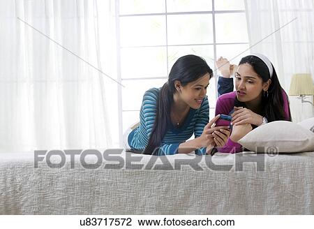Stock Image - Girls looking at an sms on a mobile phone . Fotosearch
