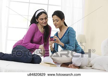 Stock Photo - Girls reading a message on a mobile phone . Fotosearch