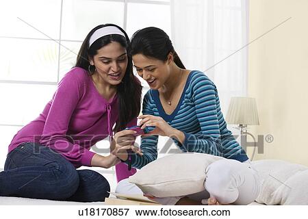 Stock Photo - Girls smiling at a message on a mobile phone . Fotosearch