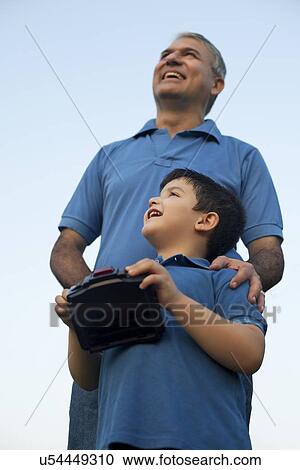Stock Image - Grandfather and Boy Playing with Radio Controlled Handset. Fotosearch