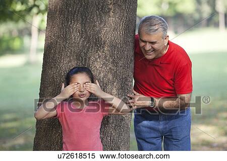 Grandfather and granddaughter playing hide and seek in a park View Large Photo Image Stock Photography - Grandfather and granddaughter playing hide and seek in a park. Fotosearch